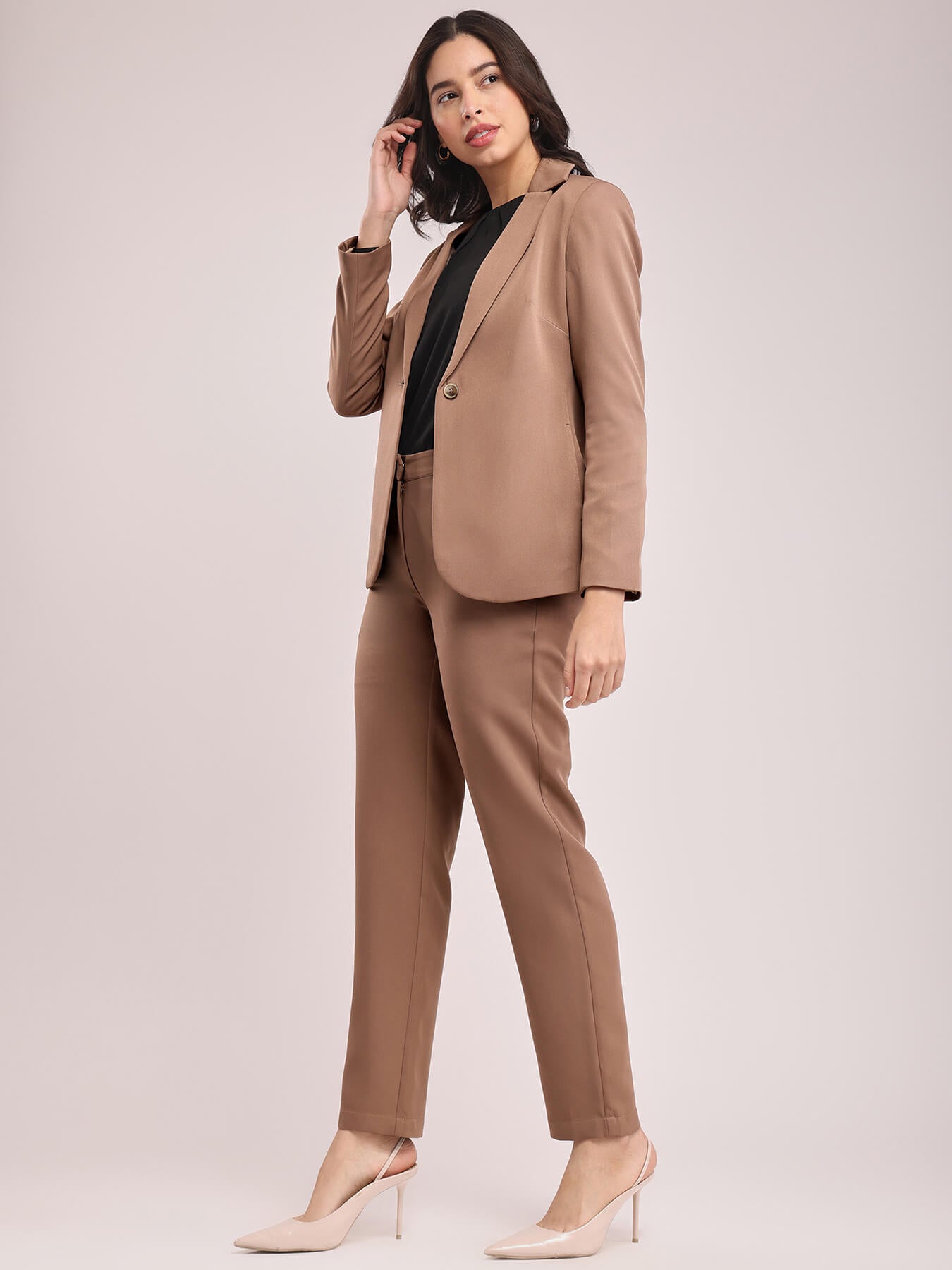 A woman modeling a brown single-breasted blazer and matching trousers, posing against a plain background. FableStreet