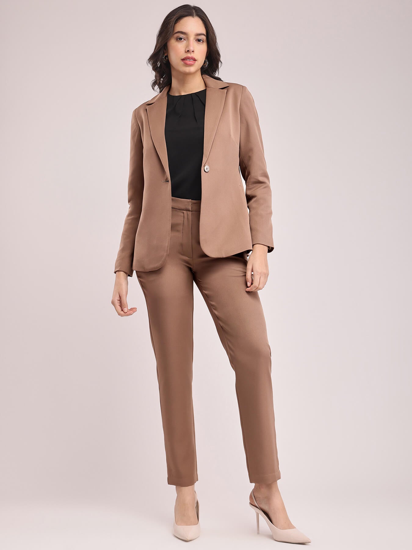 A woman modeling a brown single-breasted blazer and matching trousers, posing against a plain background. FableStreet