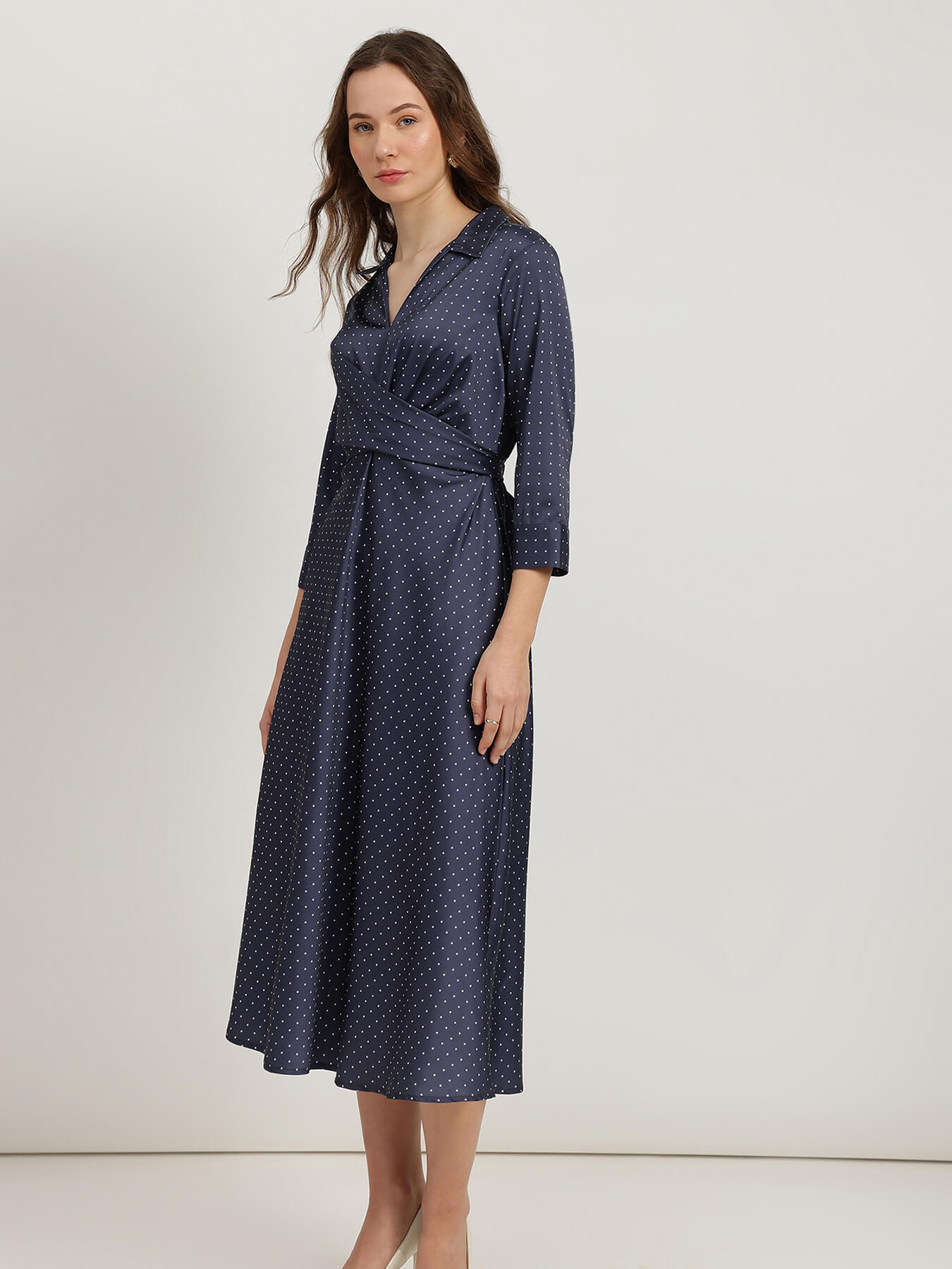 Woman wearing a navy polka dot dress on a white background