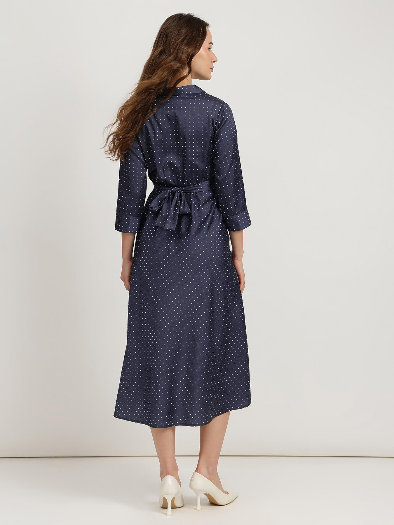 Woman wearing a navy blue polka dot dress on a white background