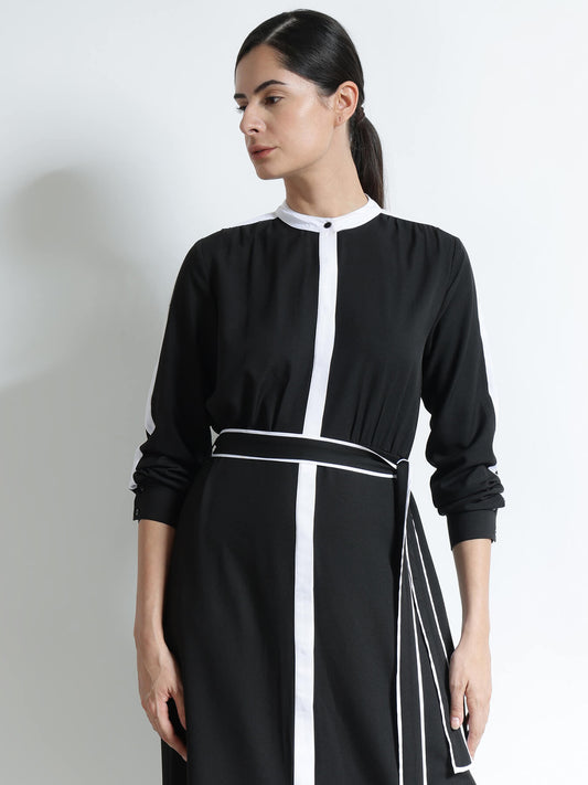 Woman wearing a black and white dress against a plain background