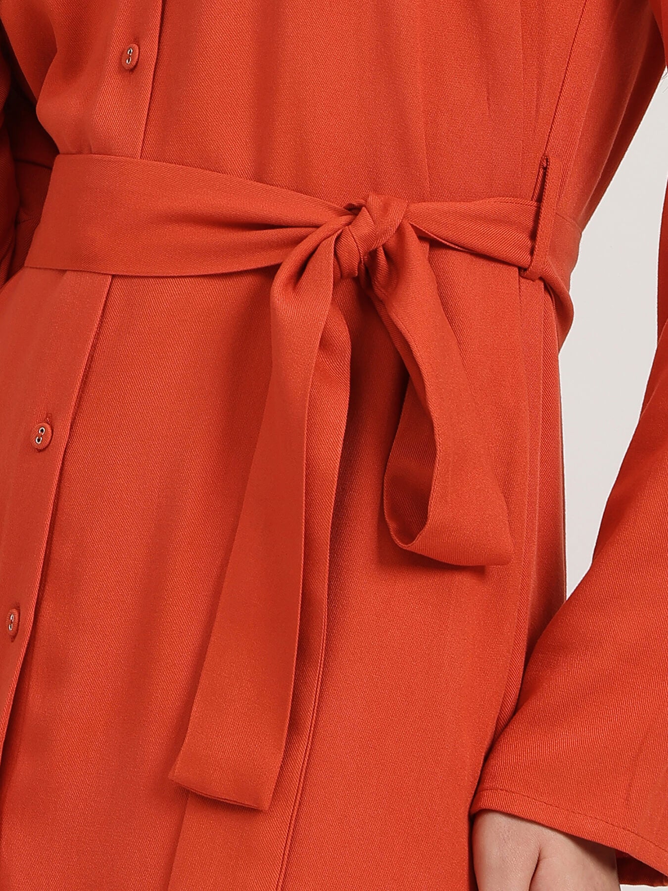 Close-up of a red dress with a belt on a white background