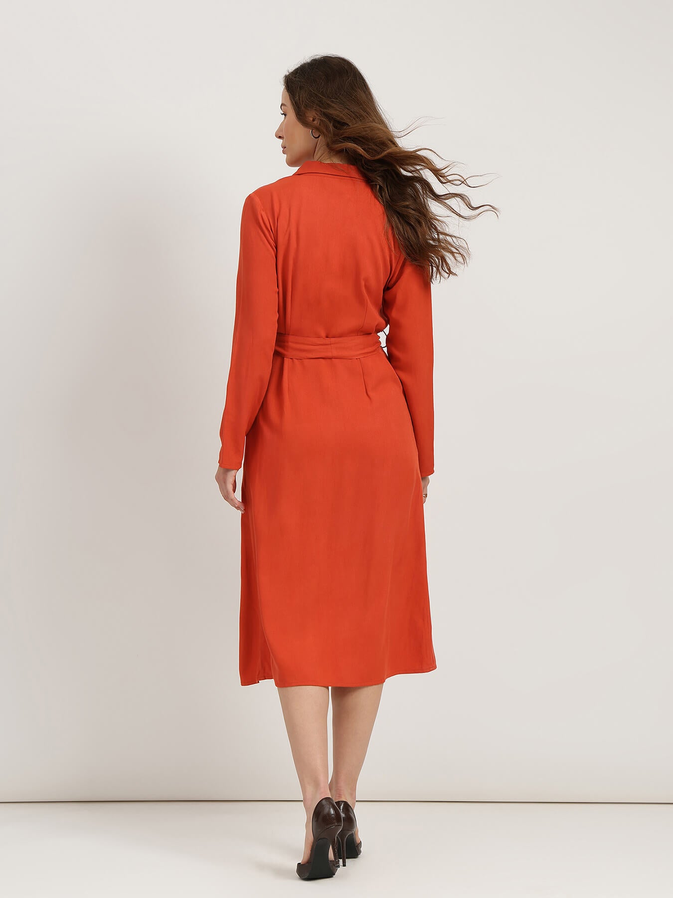 Woman wearing an orange dress against a white background