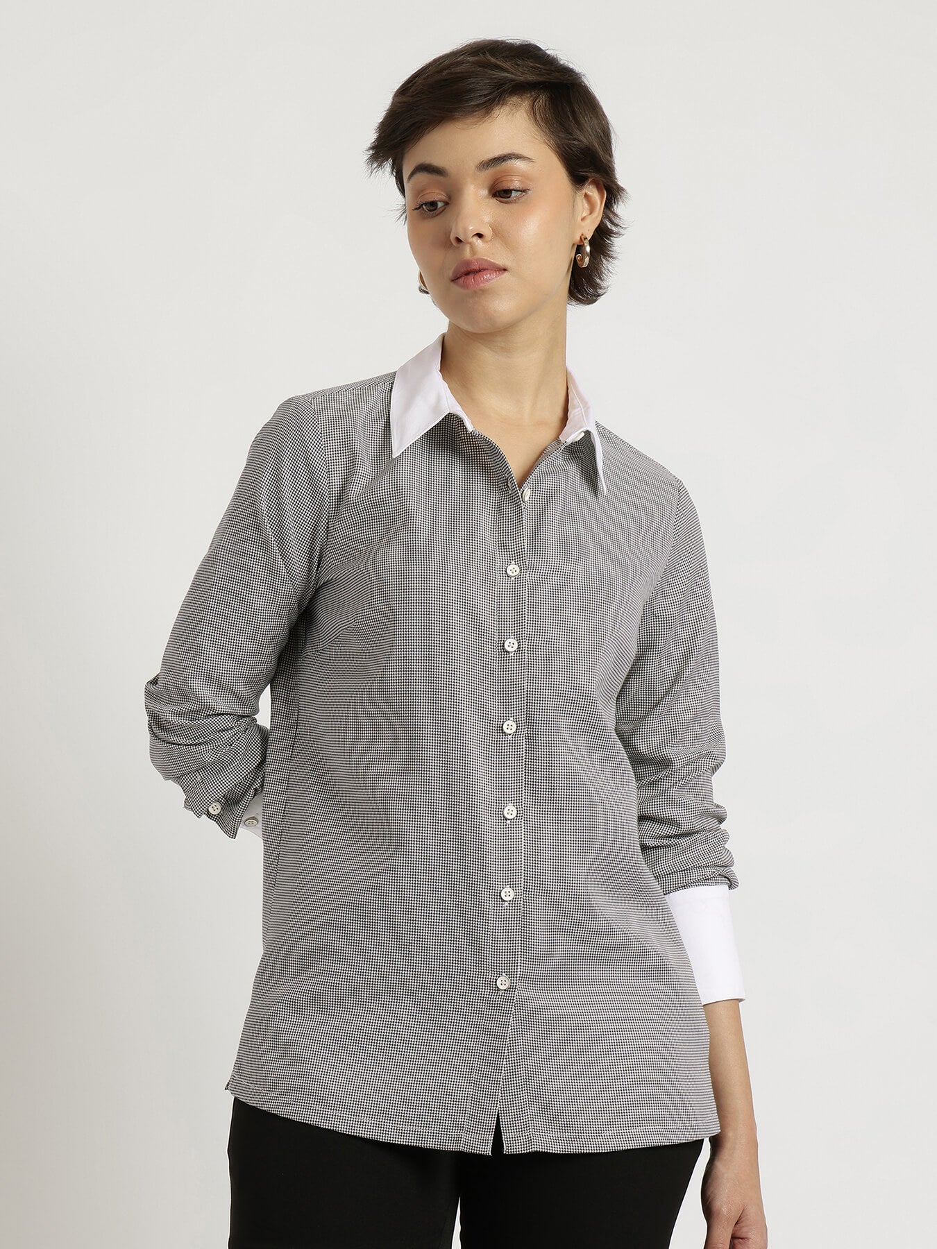 Woman wearing a gray checkered shirt with a white collar on a plain background