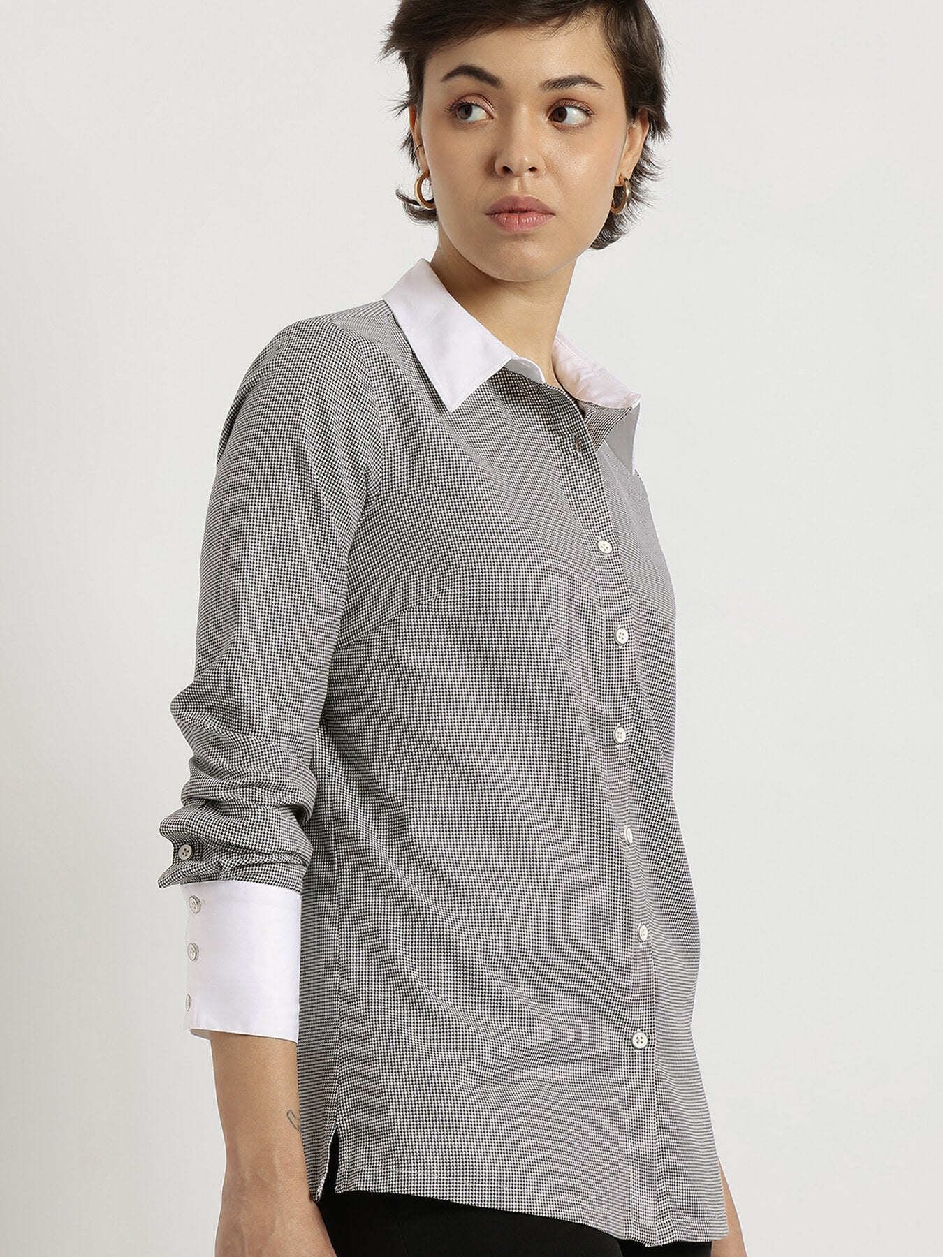 Woman wearing a gray checkered shirt with white collar and cuffs on a white background