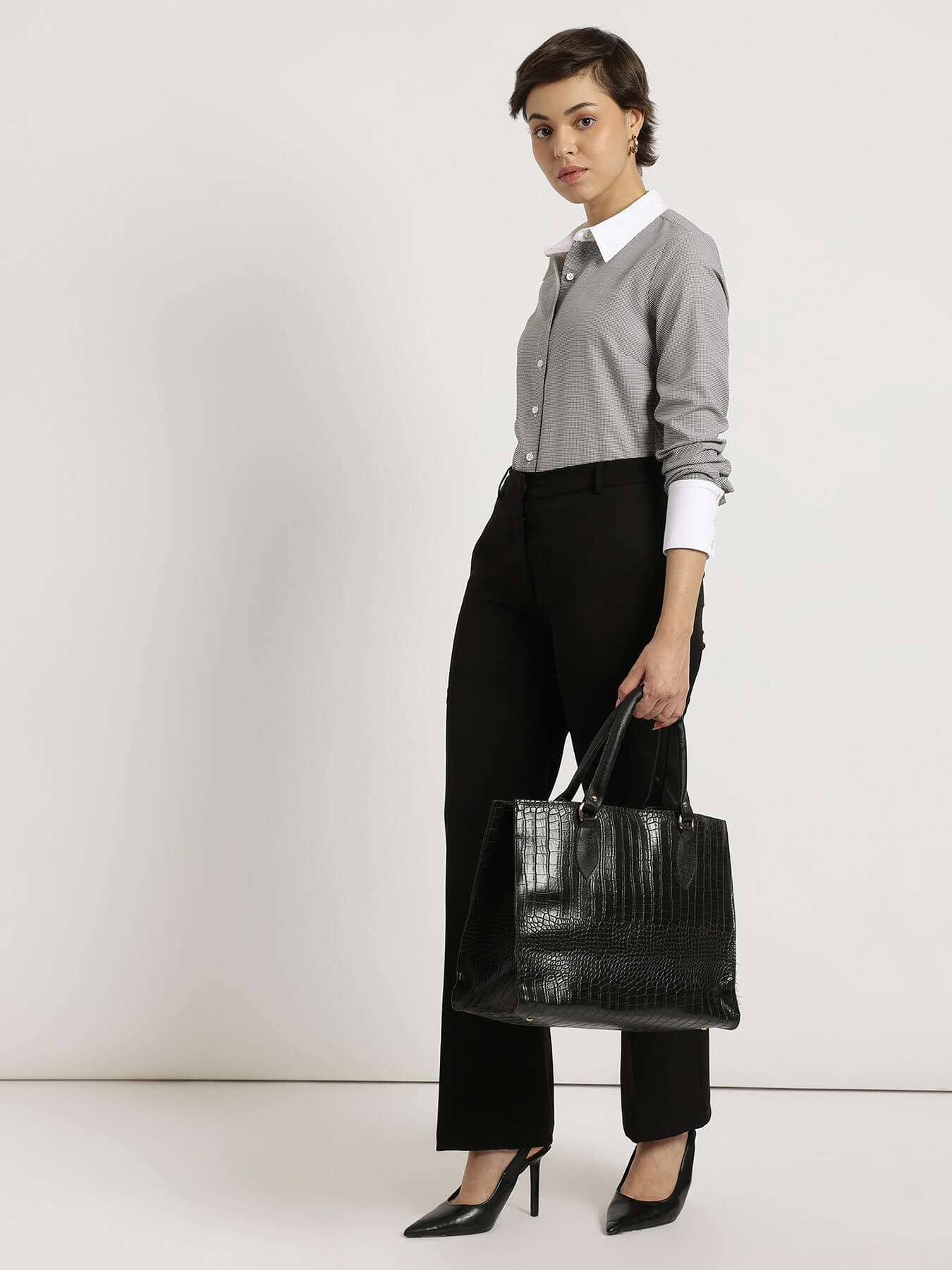 Woman holding a black handbag against a white background
