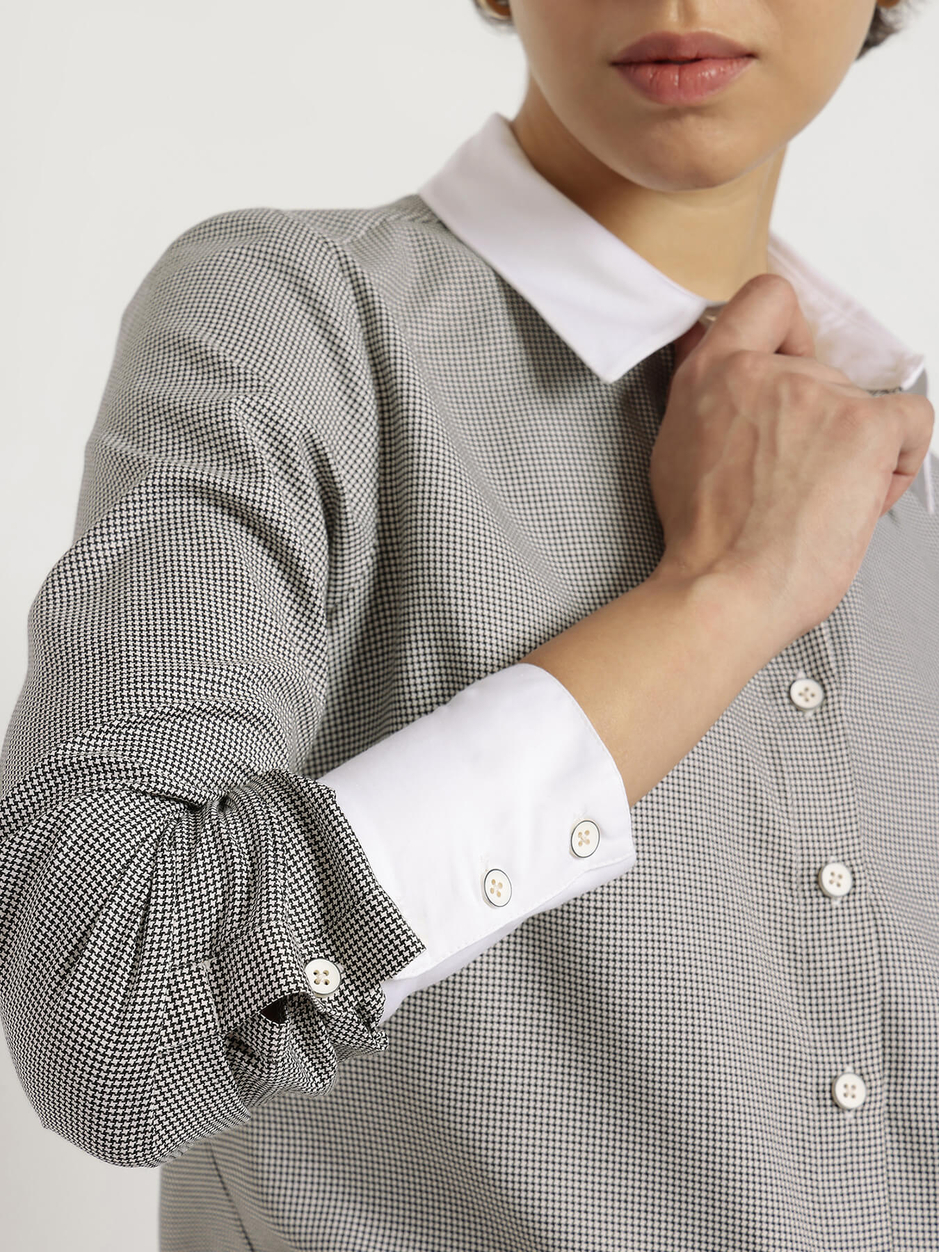 Close-up of a person wearing a checkered shirt with rolled-up sleeves and a white collar.