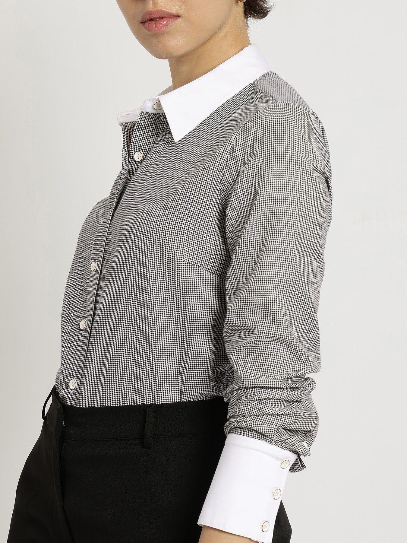 Person wearing a black and white checkered shirt with a white collar on a light gray background