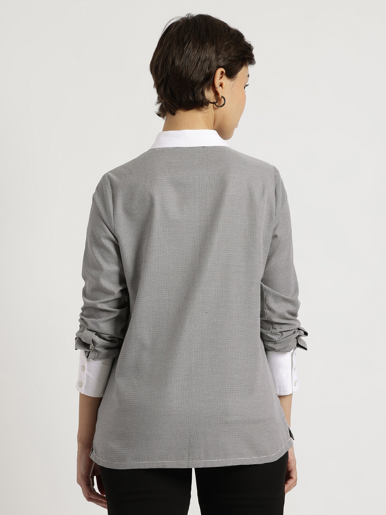 Person wearing a gray blazer over a white shirt on a plain background