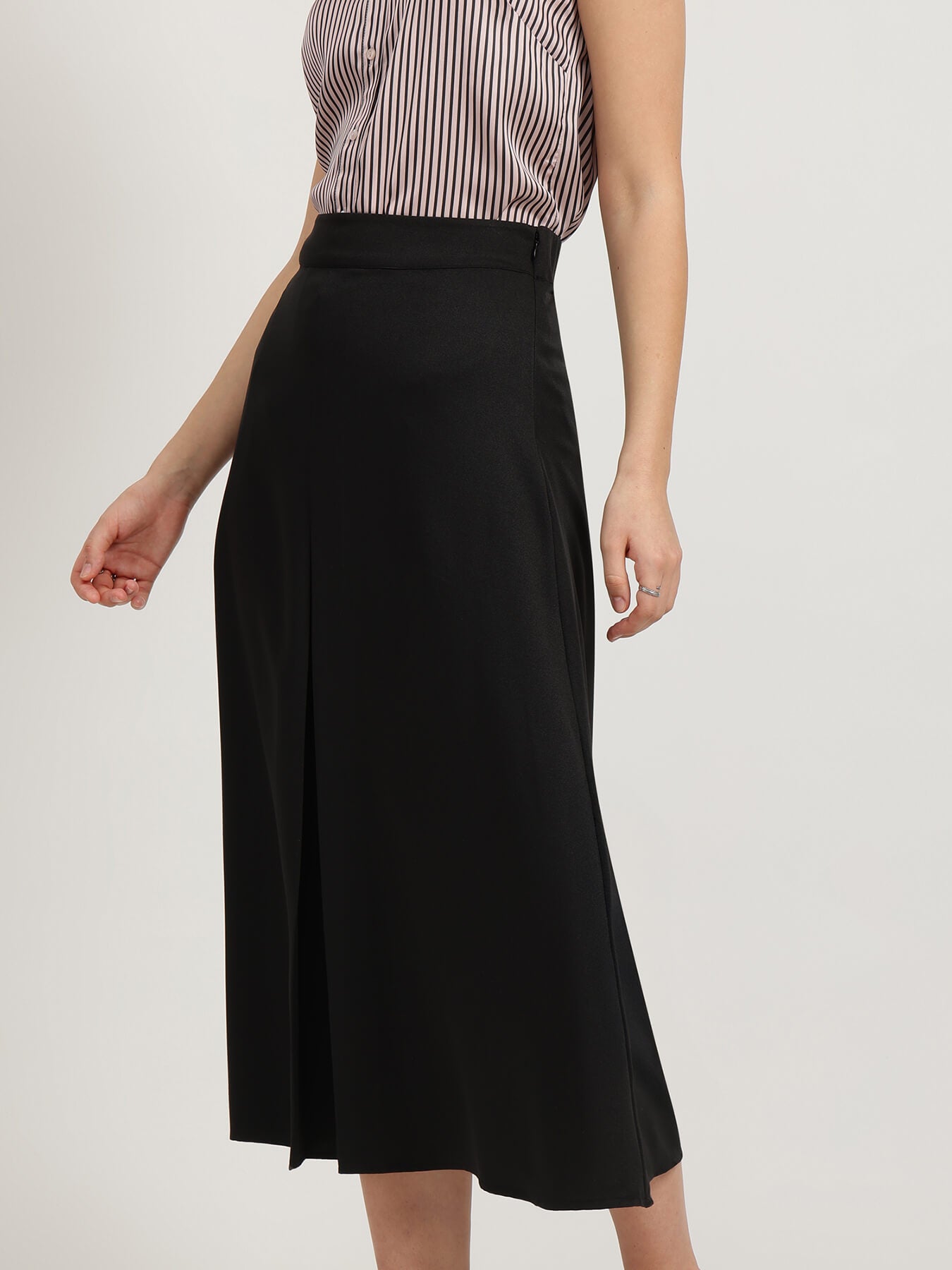Person wearing a black skirt and striped top on a plain background