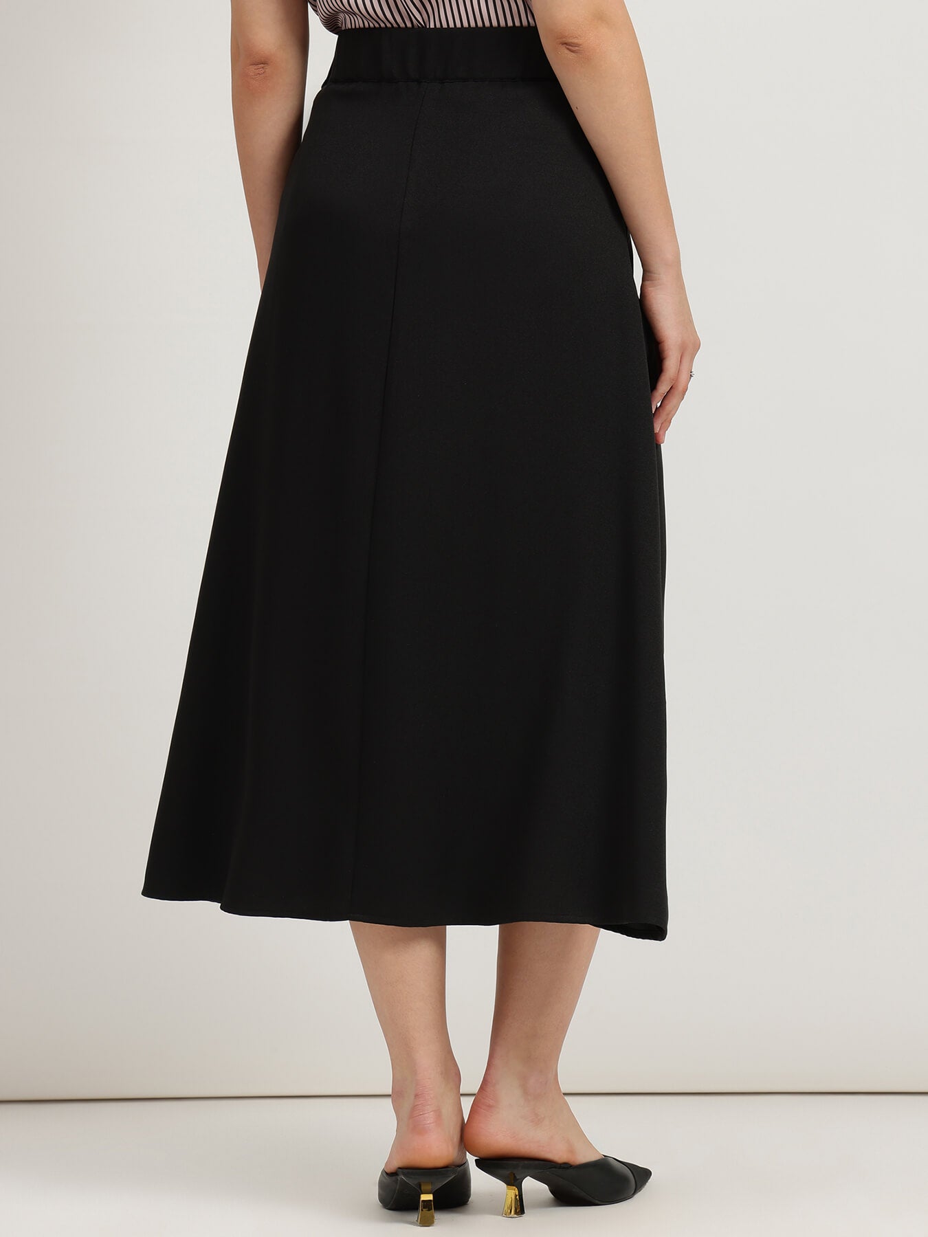 Black skirt worn by a person on a white background