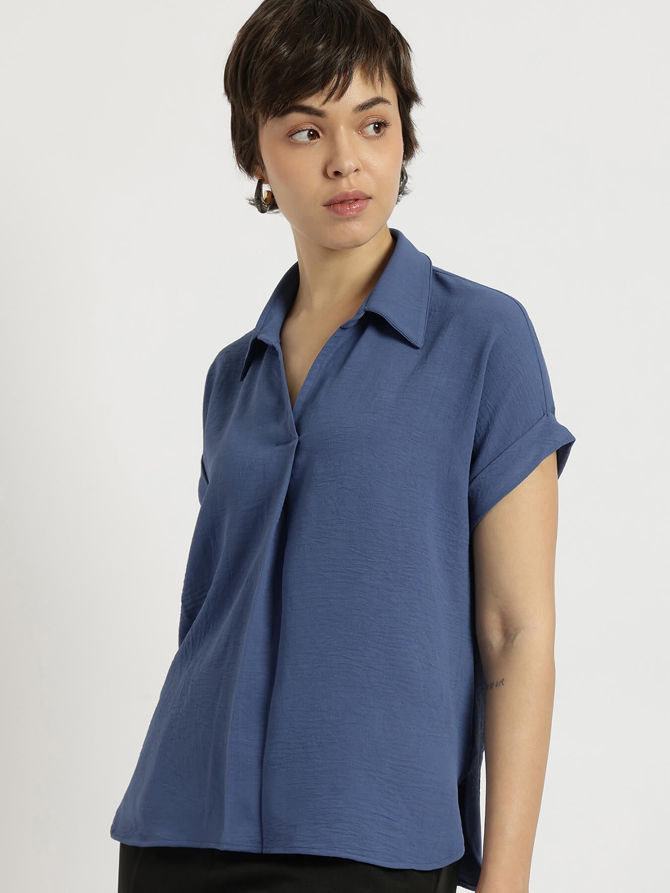 Woman wearing a blue short-sleeve shirt against a plain background