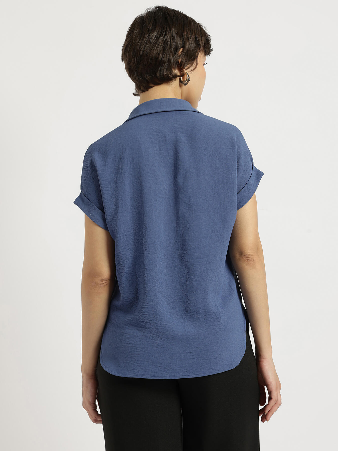 Person wearing a blue short-sleeve shirt on a plain background