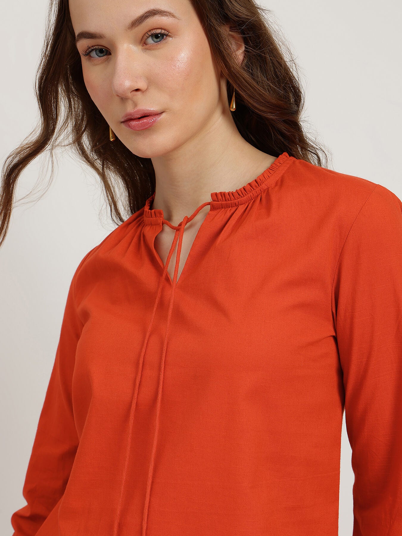 Woman wearing an orange blouse against a plain background