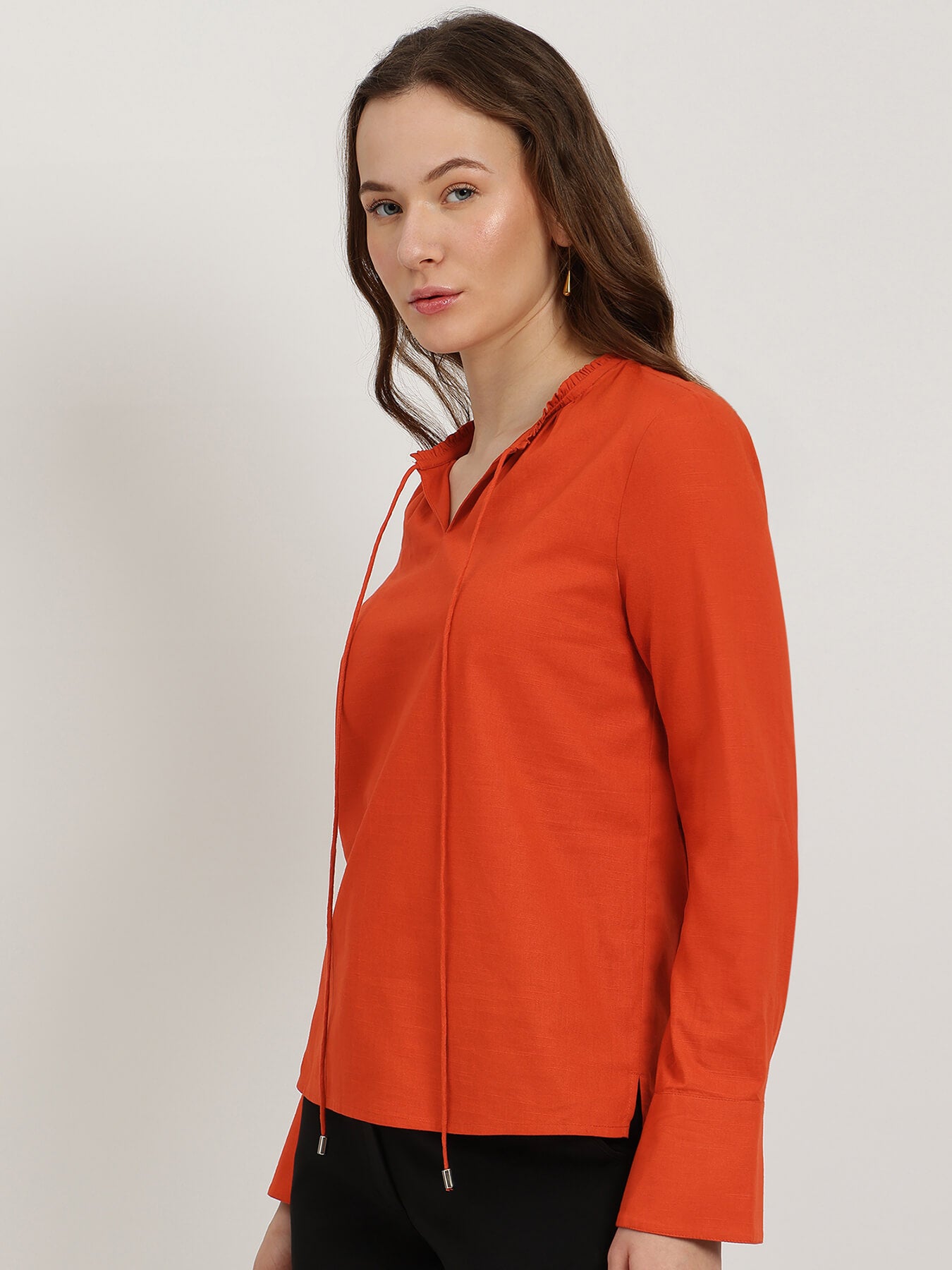 Woman wearing an orange blouse against a plain background