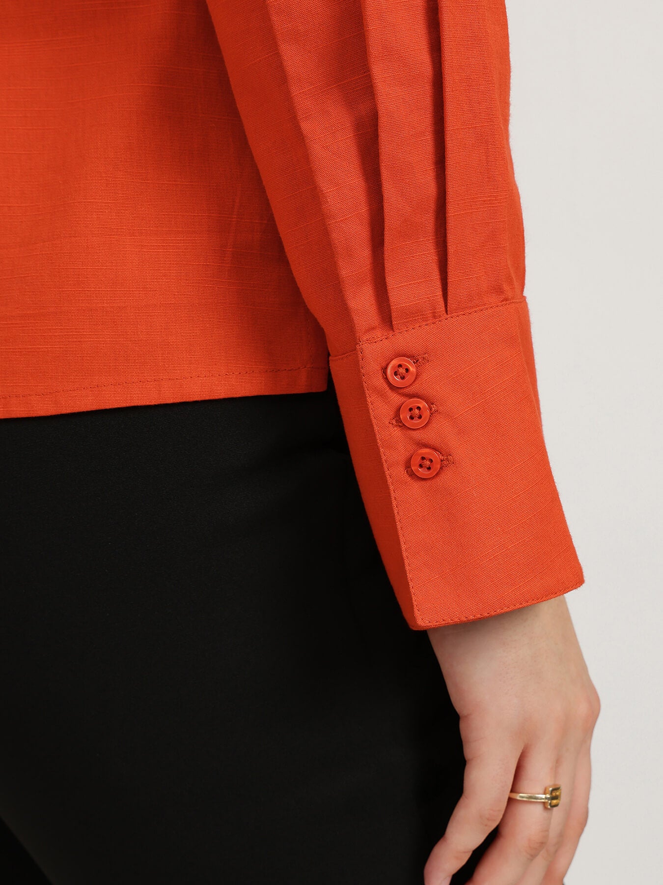 Close-up of an orange shirt with buttons on a white background