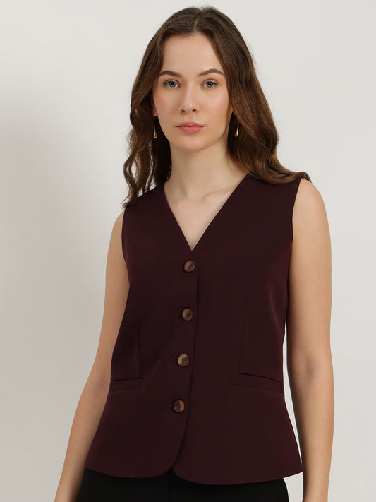 Woman wearing a sleeveless burgundy blazer against a plain background