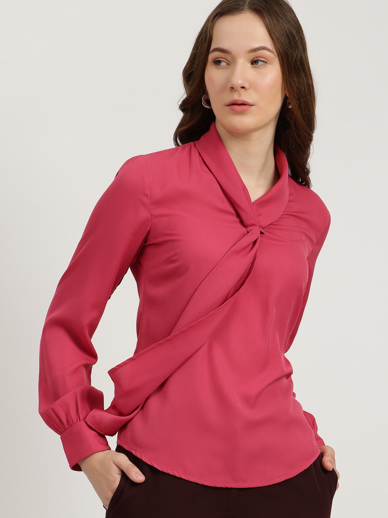 Woman wearing a pink blouse with a knot detail on a white background