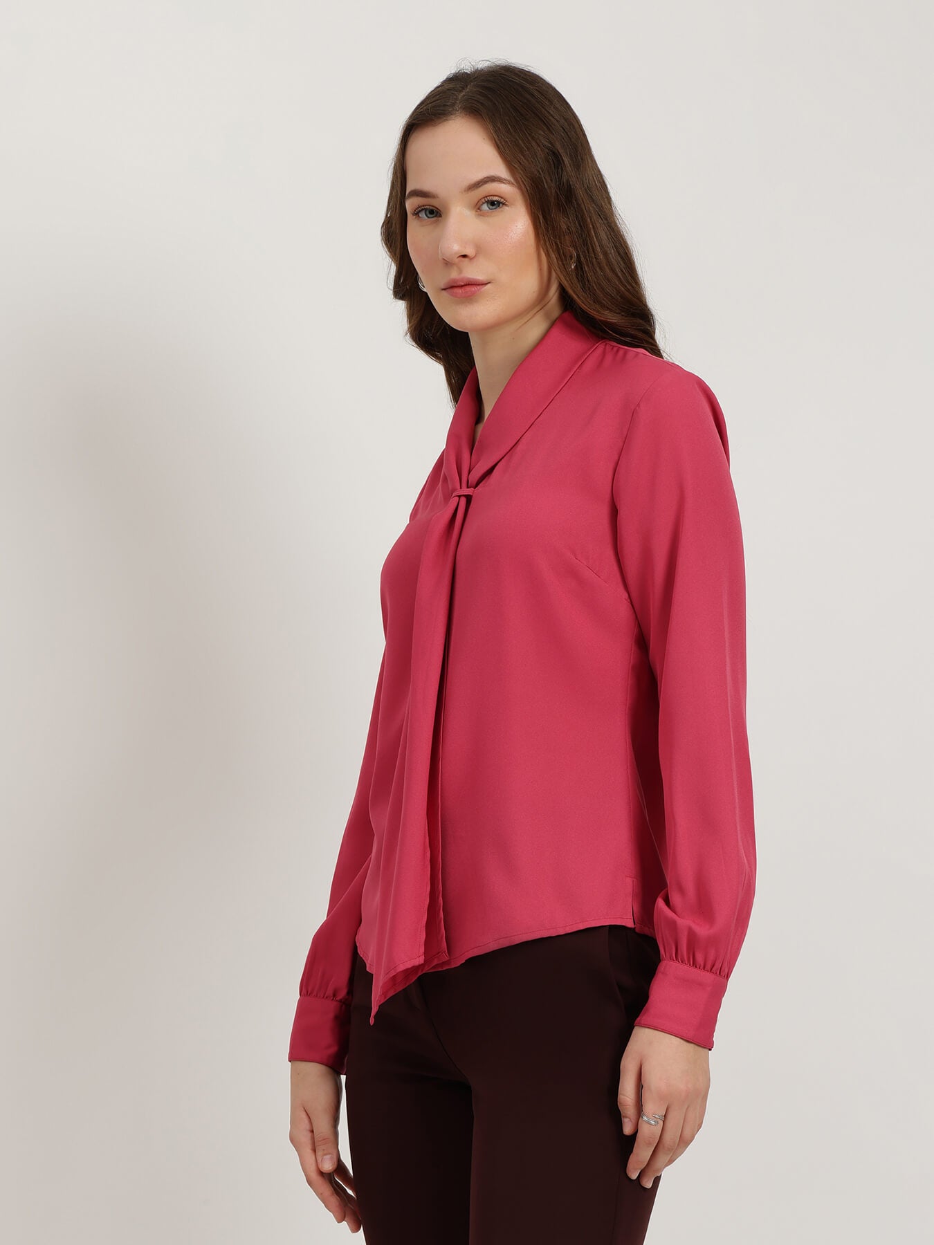 Woman wearing a pink blouse against a plain background