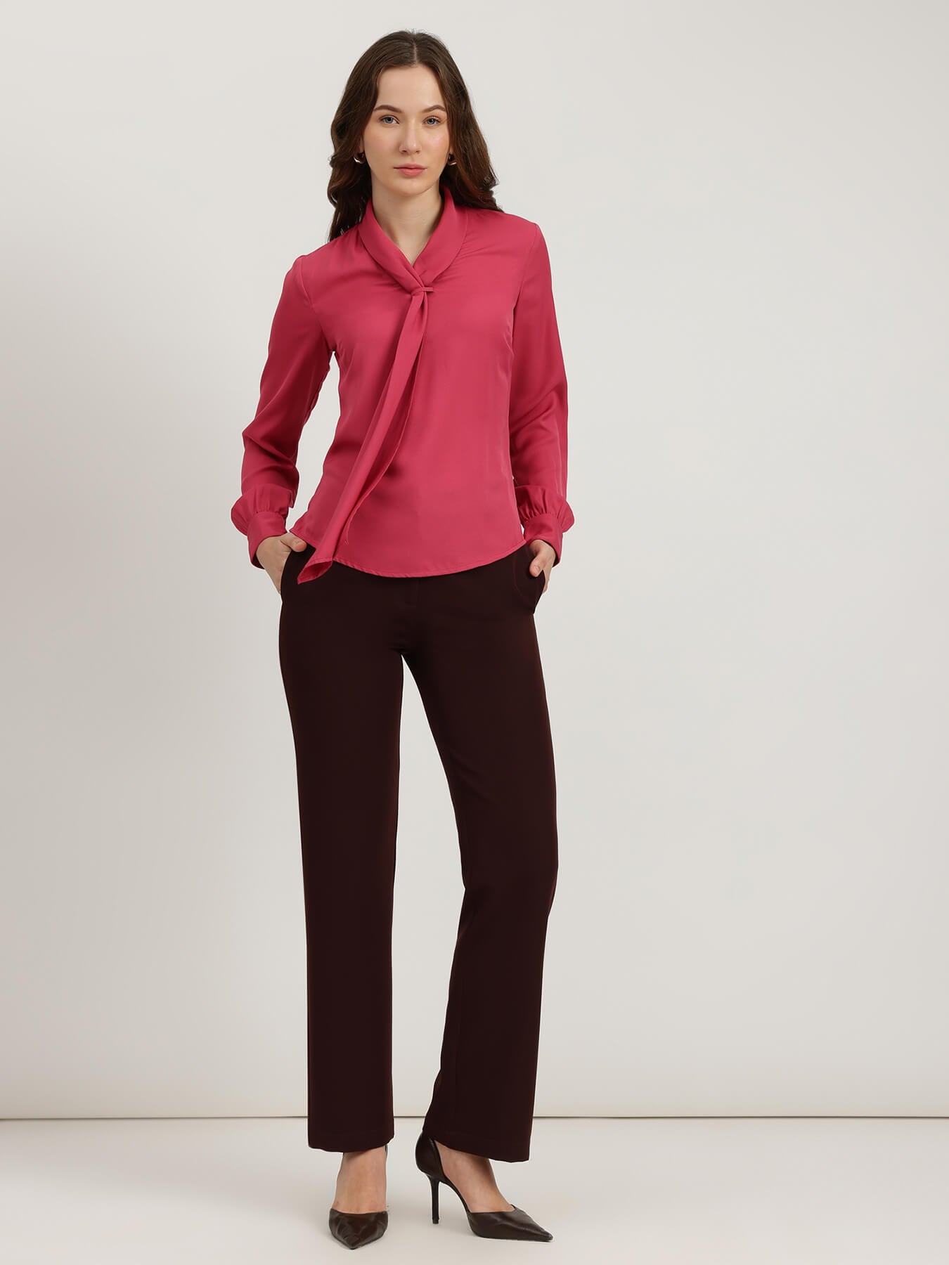Woman wearing a pink blouse and black pants on a white background