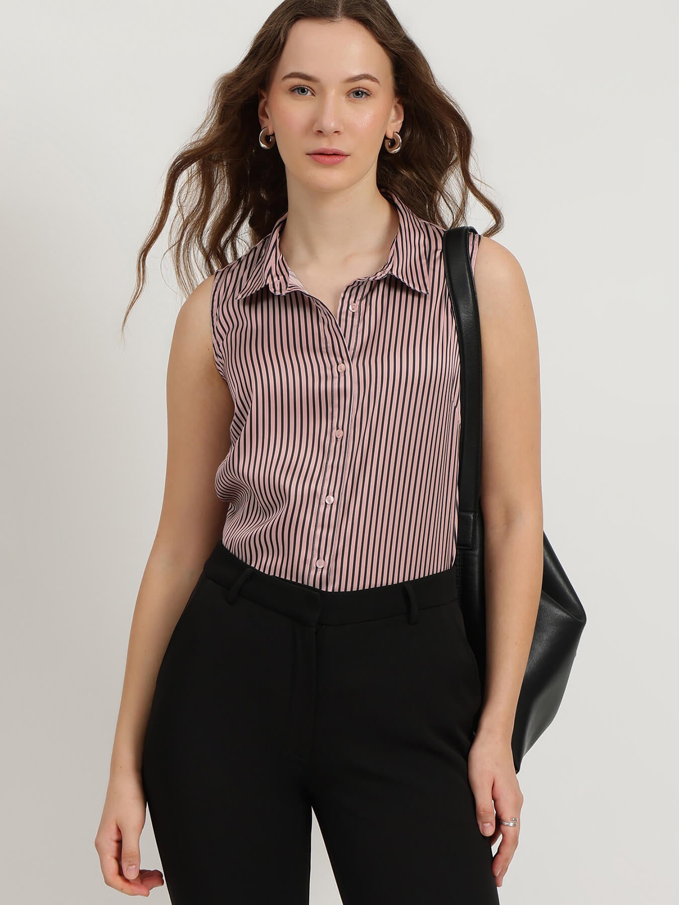 Woman wearing a sleeveless striped shirt and black pants against a plain background