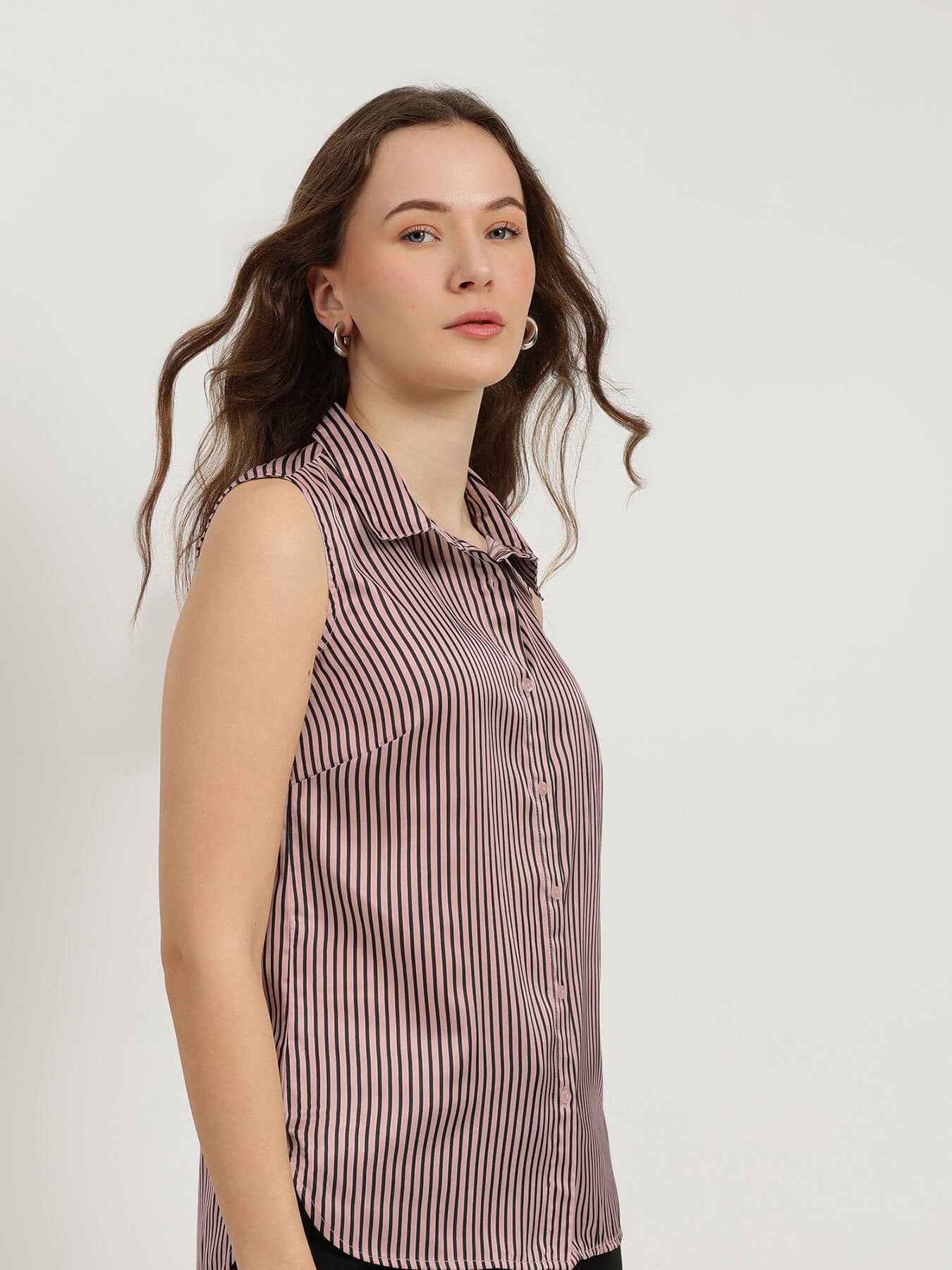 Woman wearing a sleeveless striped shirt against a plain background