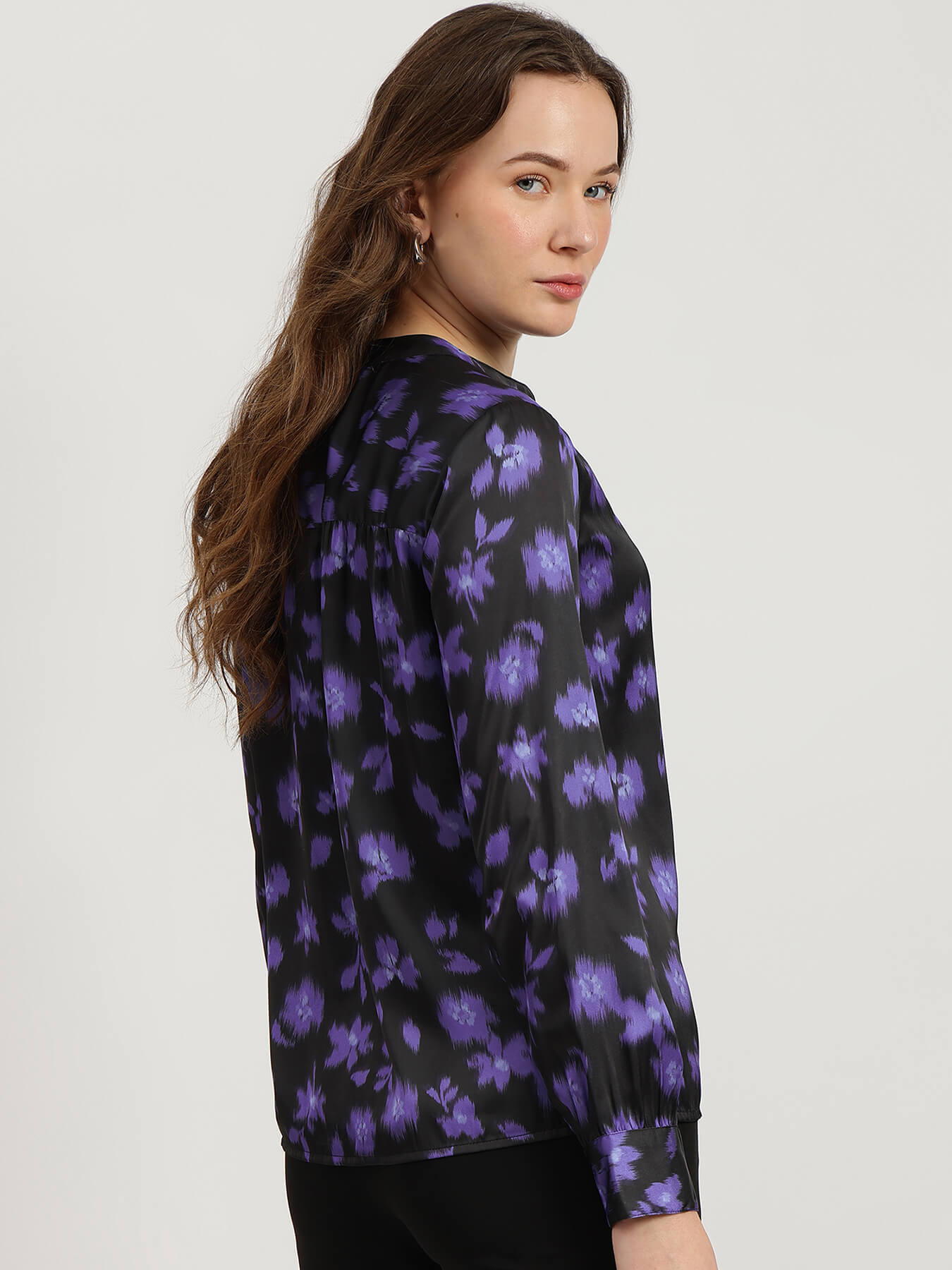 Woman wearing a black floral blouse with purple flowers on a white background