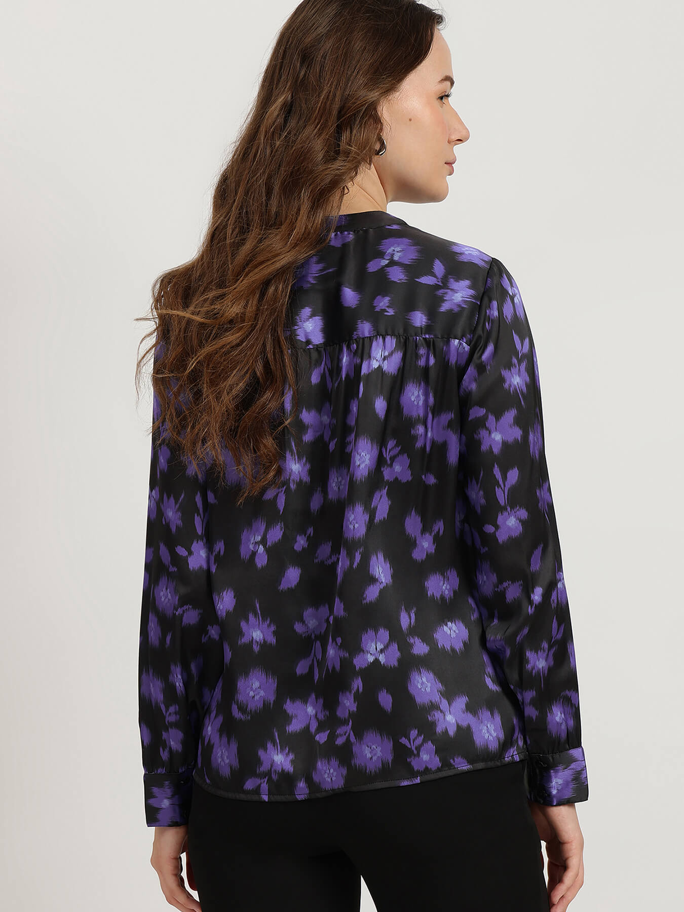 Woman wearing a black floral shirt with purple flowers on a white background