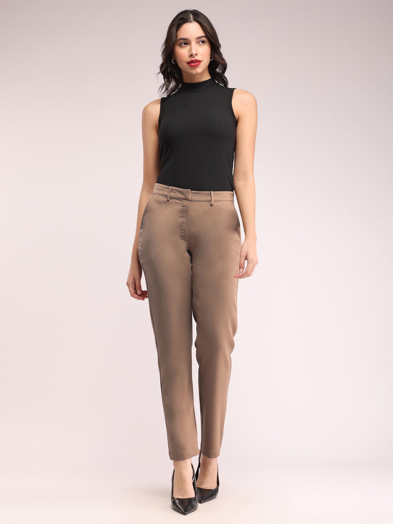 A model wearing straight fit brown trousers with a mid-rise waist, featuring pockets and made from a blend of polyester Lycra and Marina fabric.