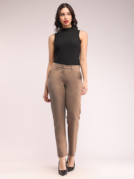 A model wearing straight fit brown trousers with a mid-rise waist, featuring pockets and made from a blend of polyester Lycra and Marina fabric.