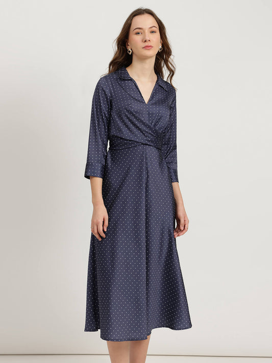 Woman wearing a navy blue dress with white polka dots on a white background