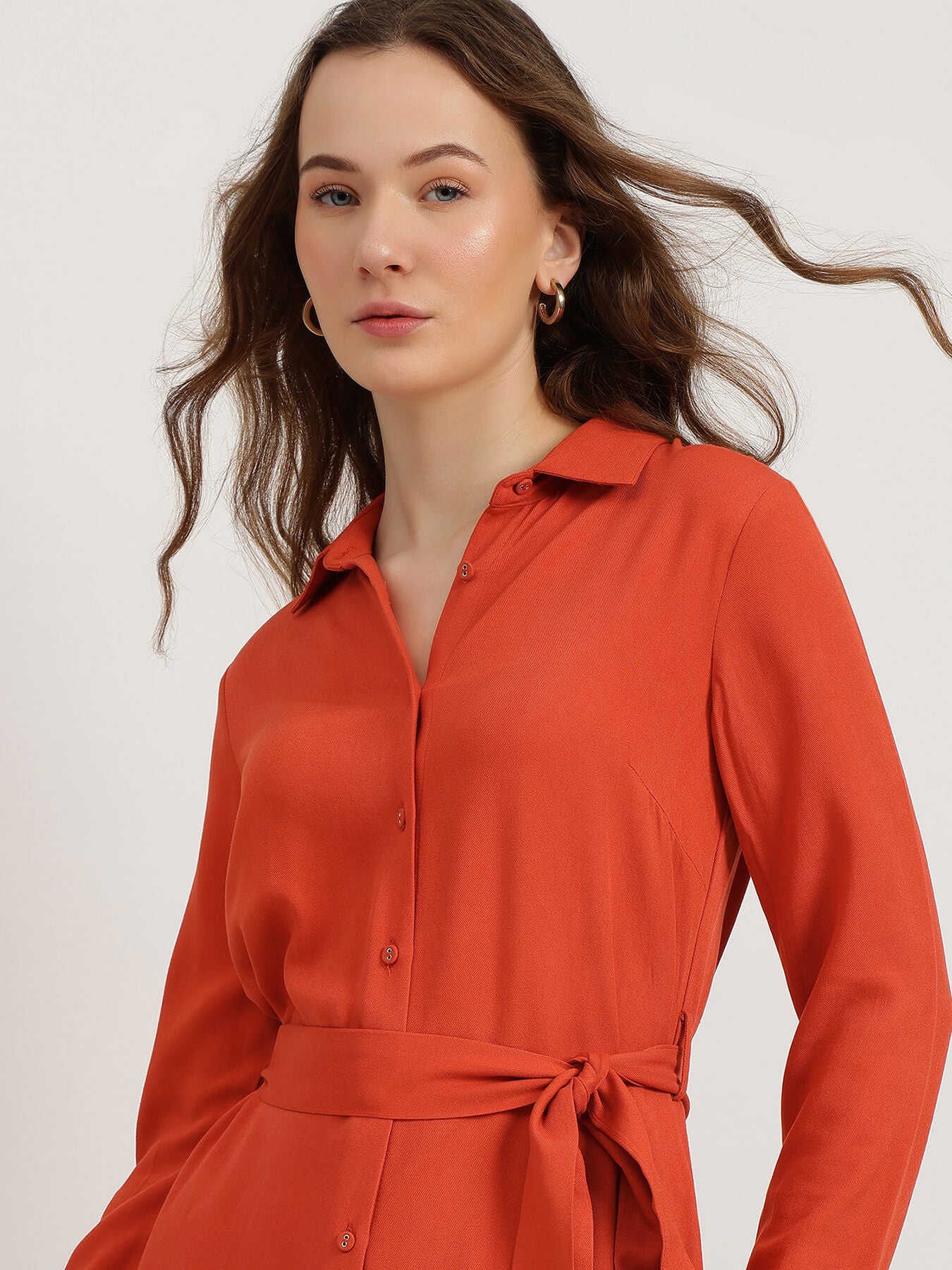 Woman wearing an orange dress against a white background
