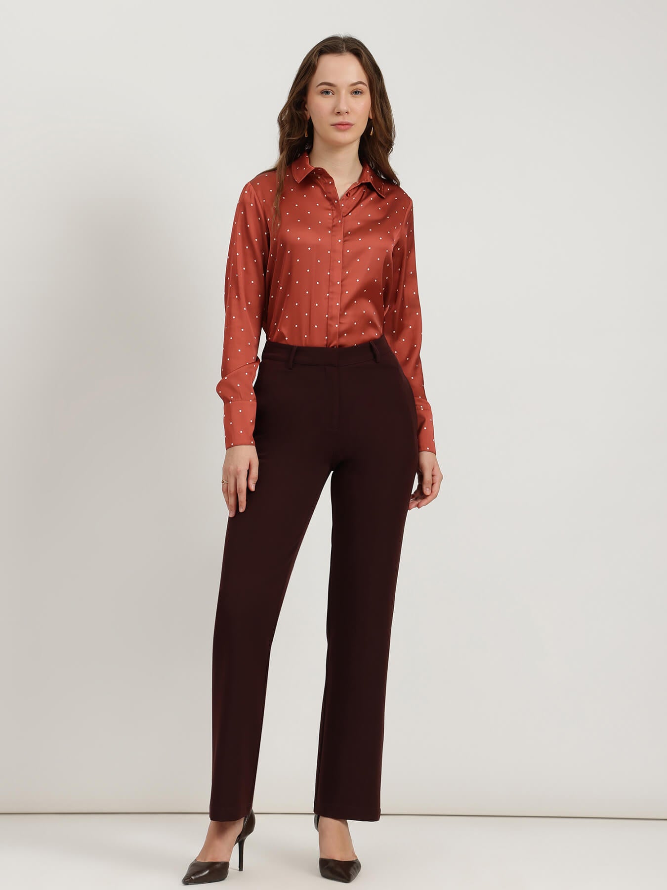 Woman wearing a red patterned blouse and black pants on a white background