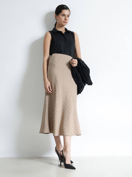 Woman wearing a black sleeveless top and beige skirt against a white background