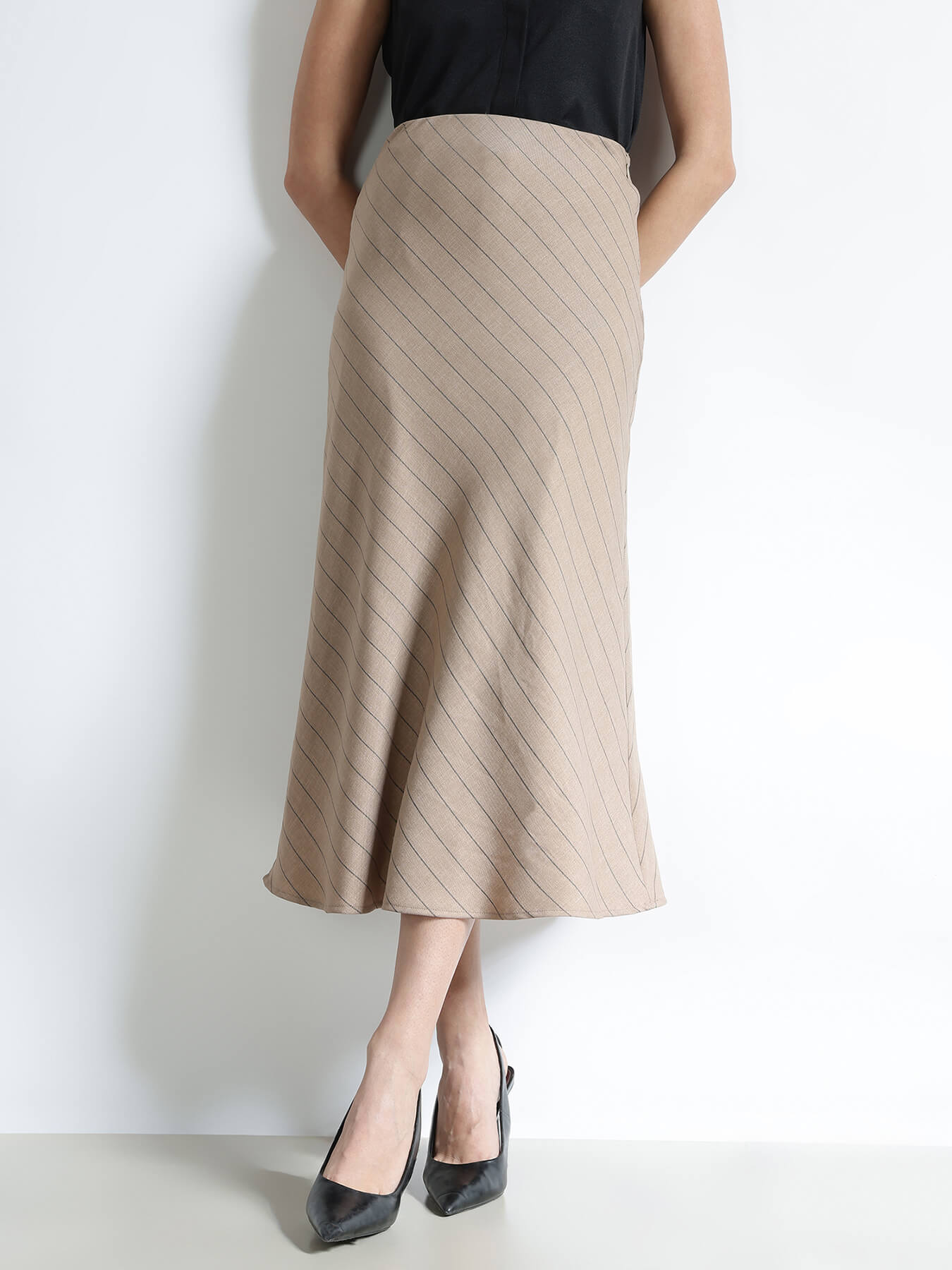 Person wearing a beige skirt with a black top on a white background