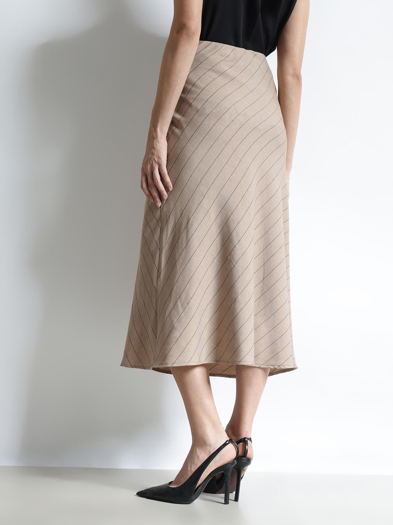 Person wearing a beige pleated skirt on a plain background