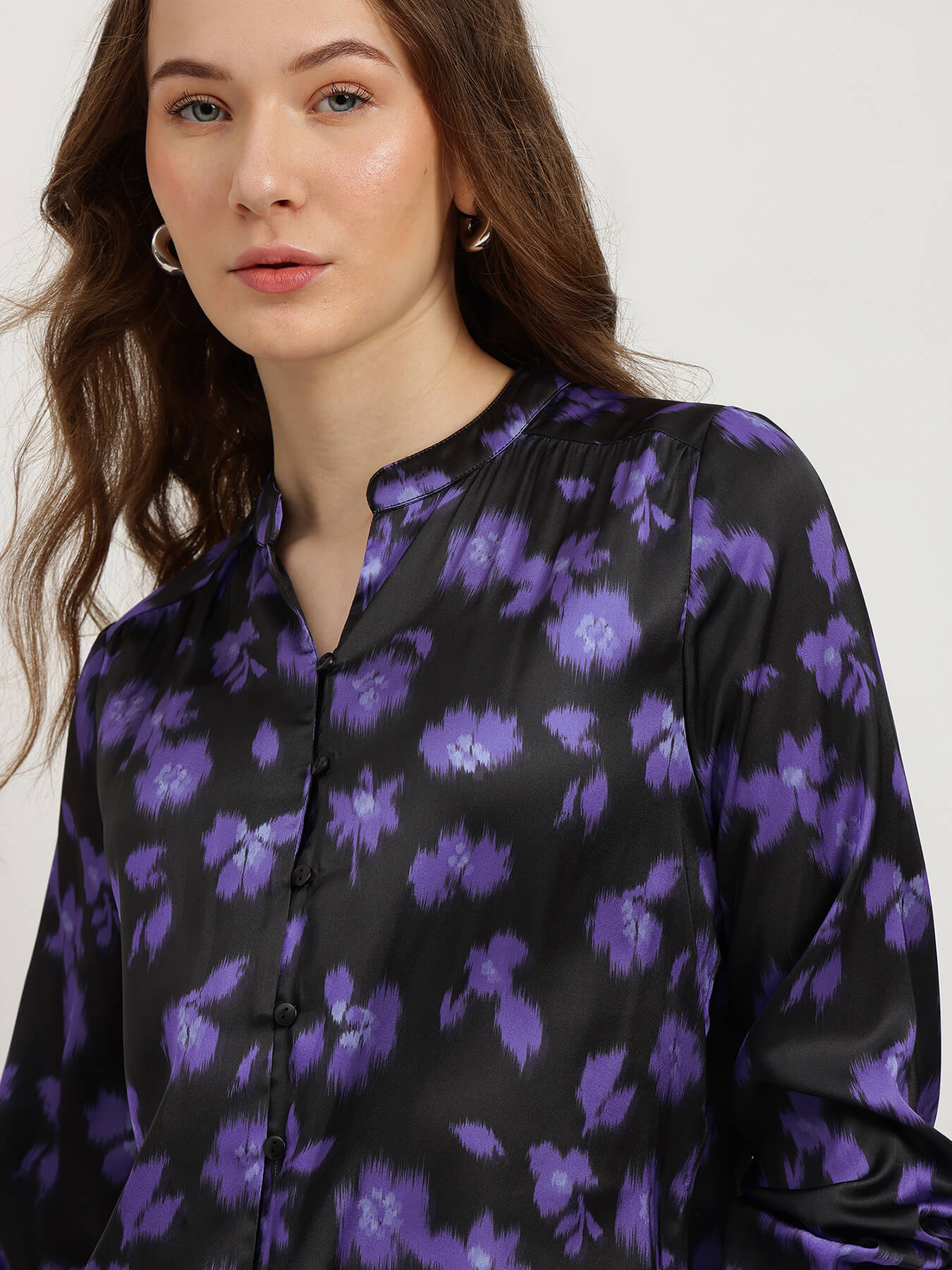 Woman wearing a black blouse with purple floral pattern on a white background