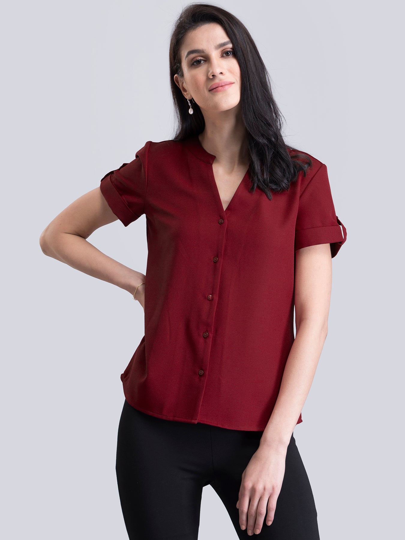 A woman wearing a red V-neck short sleeve top with a faux button detail.